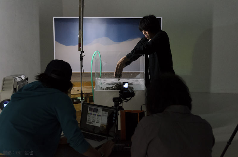 ギャラリー北を会場で行われたパフォーマンス。水槽の中で箱庭のような世界を作る様子を会場入口のスクリーンに投影した。